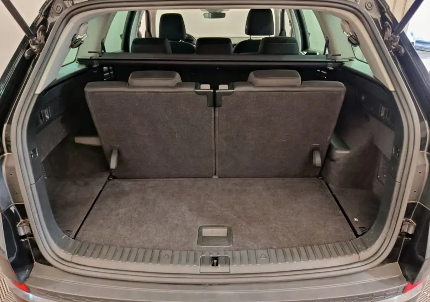 Coffre ouvert d'un Skoda Kodiaq noir 2021, montrant la 3ème rangée de sièges individuels et plancher plat.