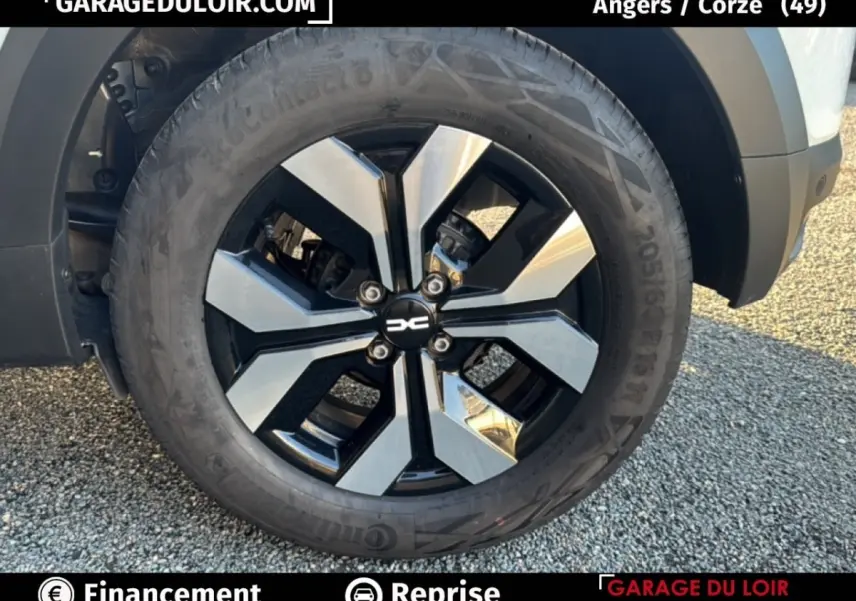 Gros plan sur la roue avant droite d'une Dacia Sandero blanche 2025 avec jante alliage bicolore moderne.