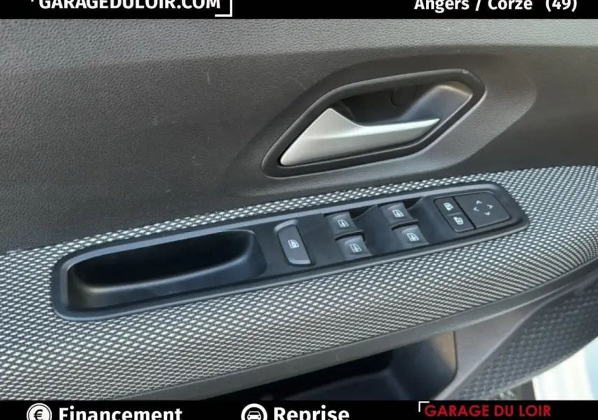Gros plan sur la commande des vitres électriques et poignée intérieure côté conducteur d’une Dacia Sandero blanche 2025.