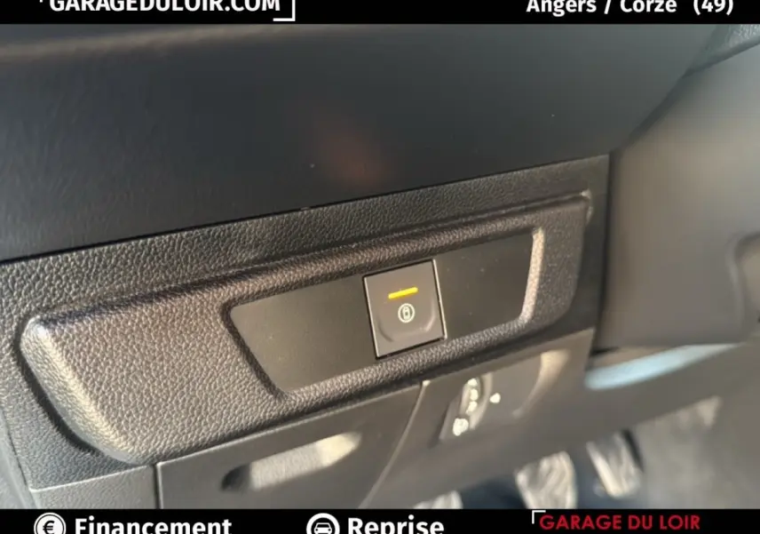 Gros plan sur le bouton de frein à main électronique dans l'habitacle noir du Dacia Sandero blanc 2025.