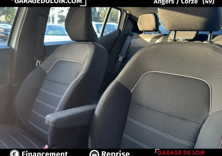 Vue intérieure sur les sièges avant en tissu gris avec surpiqûres blanches de la Dacia Sandero Expression TCe 90 2025.