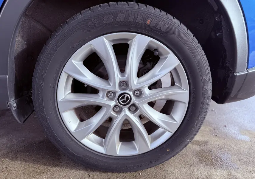 Gros plan sur la roue avant droite du Mazda CX-5 bleu 2013 avec jante alliage et pneu Sailun visible.