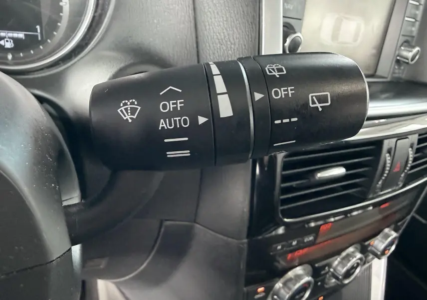 Gros plan sur la commande d’essuie-glace à gauche du volant dans l’habitacle noir du Mazda CX-5 bleu de 2013.
