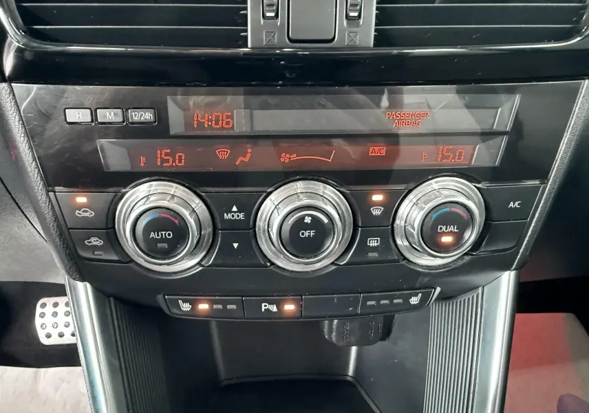 Gros plan sur la console centrale du Mazda CX-5 bleu 2013, montrant les commandes de climatisation et les voyants allumés.