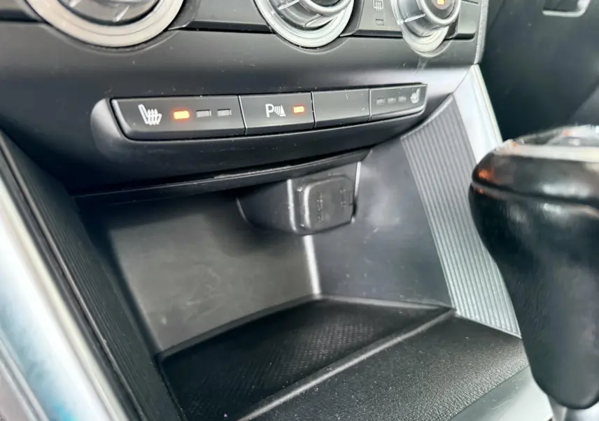 Gros plan sur la console centrale intérieure du Mazda CX-5 2013, montrant les commandes de sièges chauffants et la prise 12V.