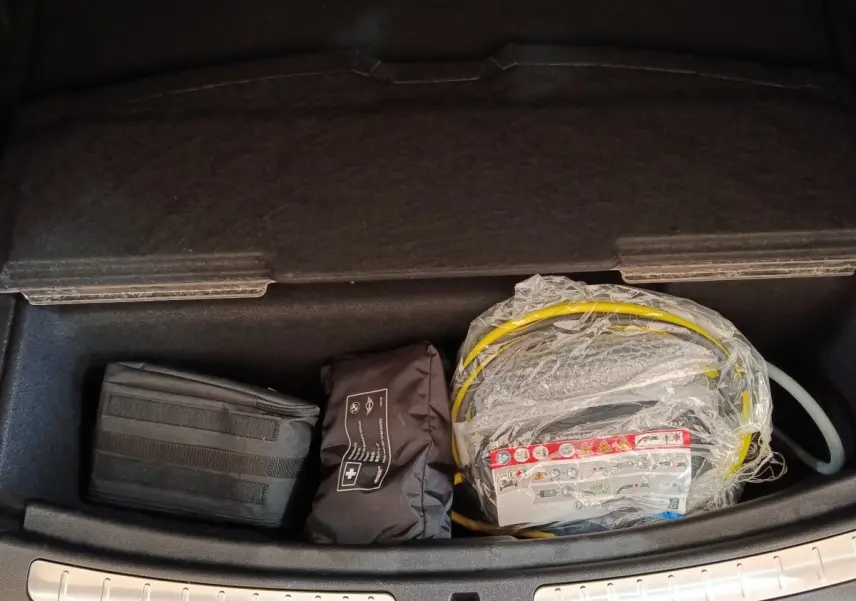 Vue plongeante sur le rangement réfrigéré noir du coffre du MINI Countryman Cooper SE 2023 avec câble de charge emballé.