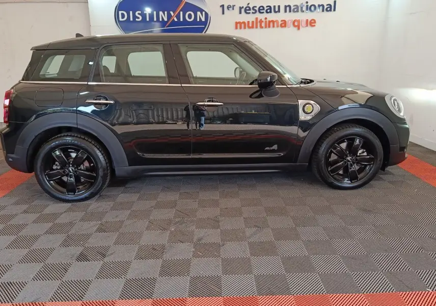 Vue de profil côté gauche d'un MINI Countryman Cooper SE noir avec jantes noires brillantes et logo ALL4 visible.