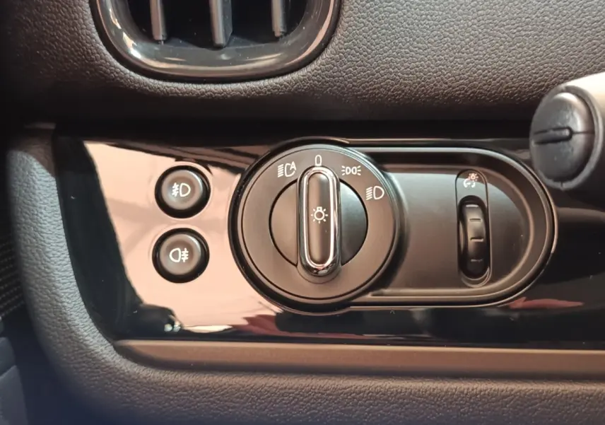 Gros plan sur les commandes d’éclairage du tableau de bord noir du MINI Countryman Cooper SE 2023.