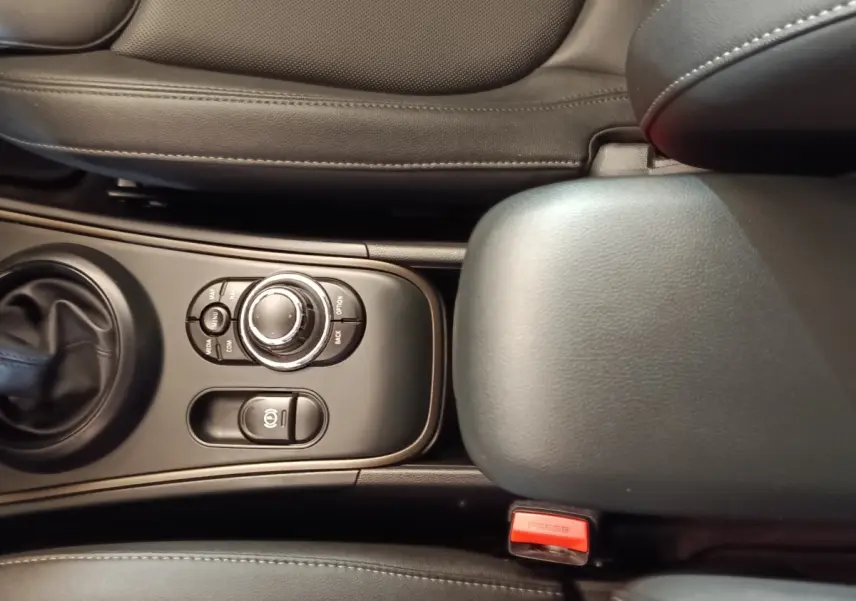 Vue rapprochée de la console centrale noire du MINI Countryman 2023, avec commandes et accoudoir en cuir.