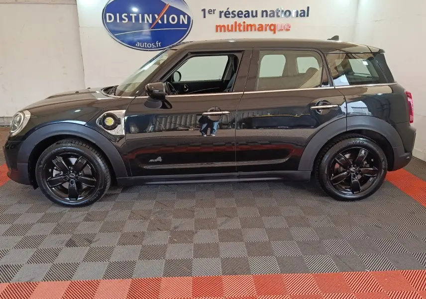 Vue de profil côté gauche d'une MINI Countryman Cooper SE noire avec jantes noires et badge hybride visible.