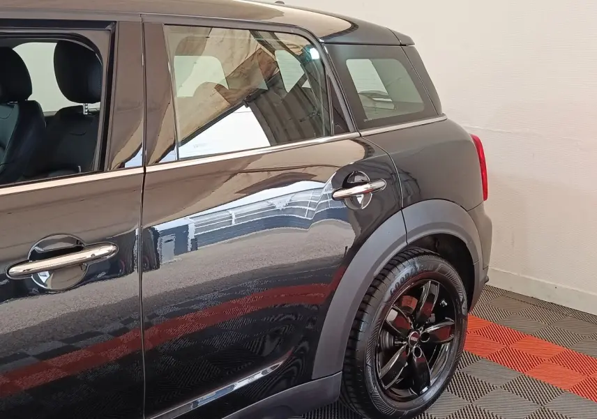 Vue latérale droite du MINI Countryman Cooper SE noir, mettant en valeur la roue arrière et les poignées chromées.