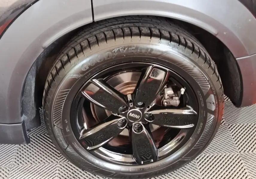 Gros plan sur la roue avant gauche noire brillante d’un MINI Countryman Cooper SE 2023 avec pneu Goodyear.