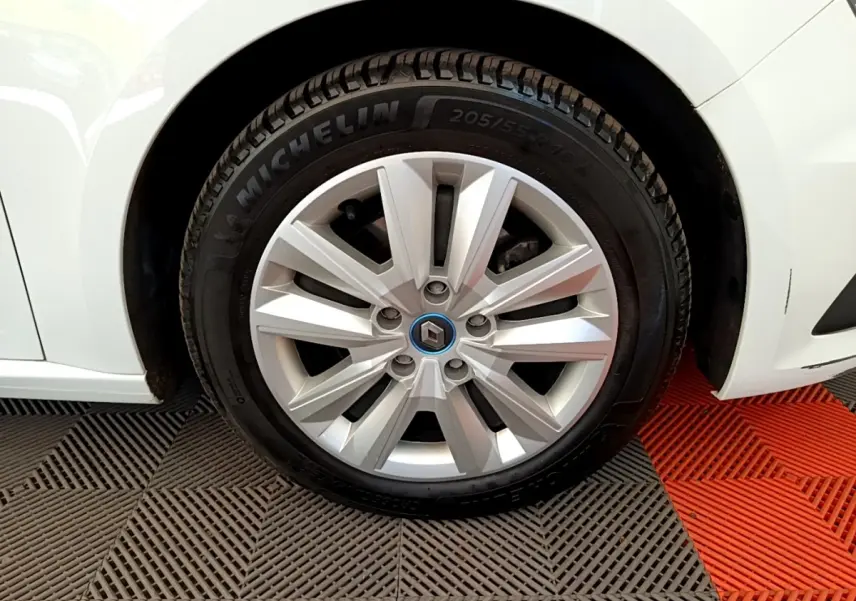 Gros plan sur la roue avant droite d’une Renault Mégane Business E-Tech hybride blanche avec jante argentée et logo Renault bleu.