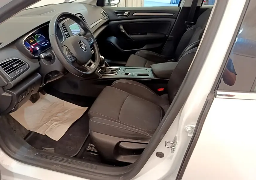 Vue intérieure côté conducteur d'une Renault Mégane Business E-Tech blanche, avec tableau de bord digital et sièges noirs.
