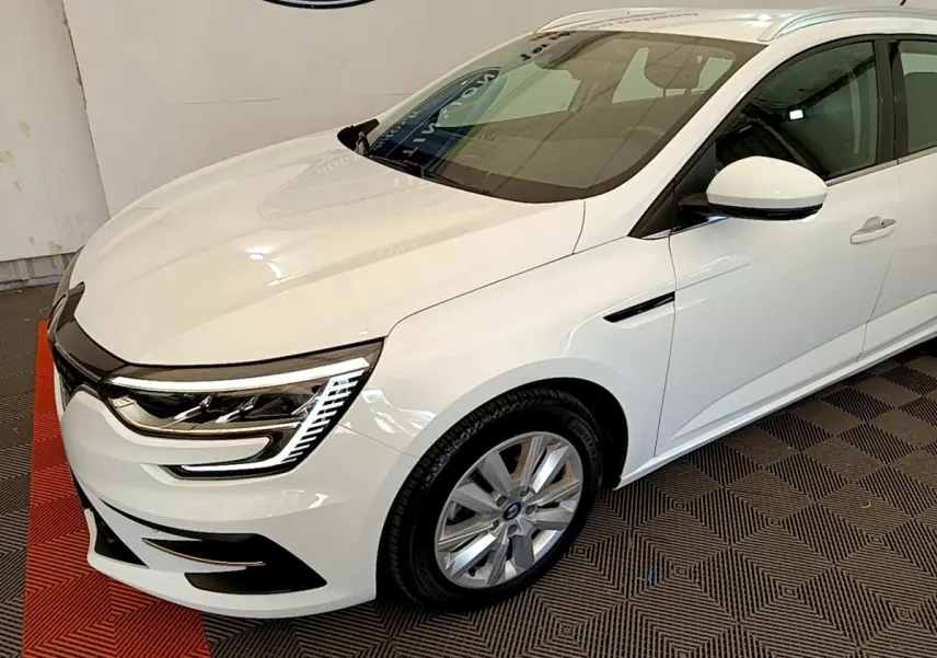 Vue 3/4 avant droite d'une Renault Mégane Business E-Tech hybride rechargeable blanche avec feux LED distinctifs et jantes alliage.