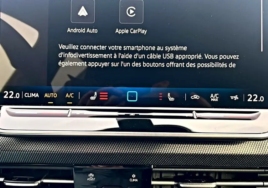 Vue rapprochée de l’écran tactile central et commandes de climatisation d’une Volkswagen Golf noire 2026.