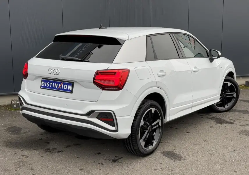 Audi Q2 blanc Glacier vue 3/4 arrière droit avec jantes noires 5 branches doubles et vitres surteintées.