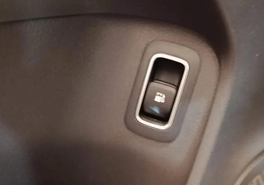 Gros plan sur le bouton d’ouverture de trappe à carburant dans l’habitacle gris foncé d’une Mercedes Classe A 250 e 2023.