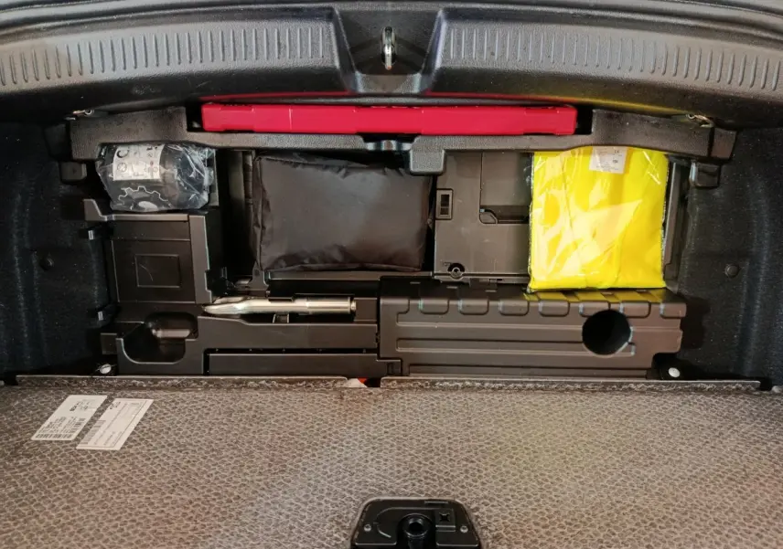 Coffre ouvert d'une Mercedes Classe A 250 e Business Line gris clair, montrant le rangement sous plancher avec kit de sécurité.