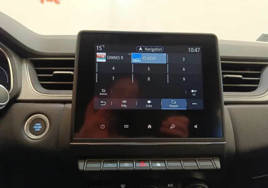 Vue rapprochée de l’écran tactile central du tableau de bord du Renault Captur Intens E-TECH gris clair, avec bouton démarrage visible.
