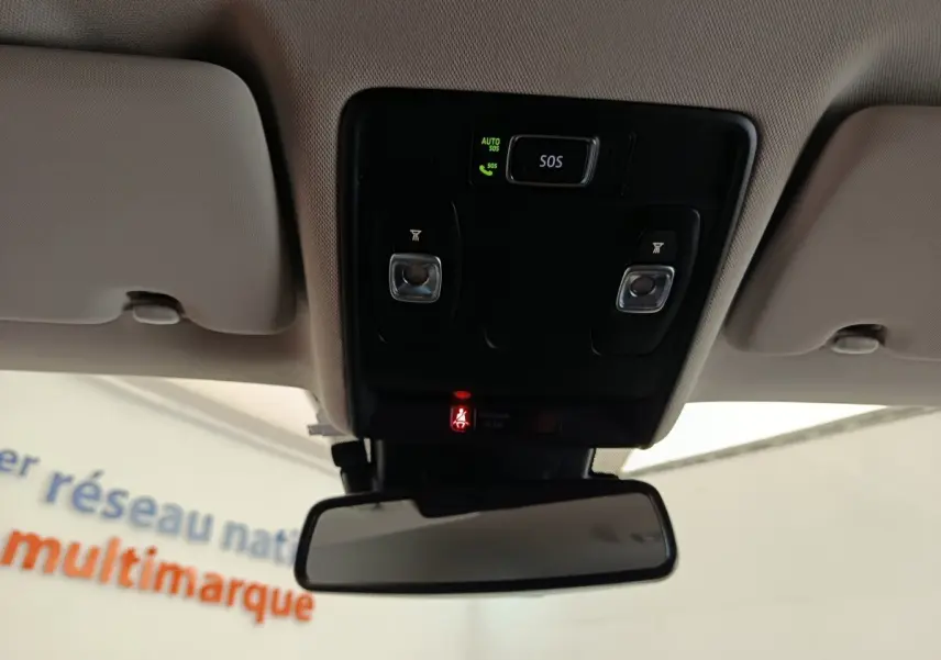 Vue intérieure centrée sur le plafonnier avec boutons SOS et éclairage, rétroviseur intérieur et ciel de toit beige.