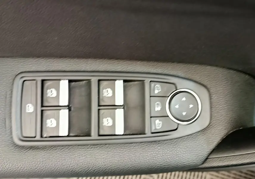 Panneau de commandes des vitres électriques et rétroviseurs sur la porte côté conducteur d'un Renault Captur gris clair.