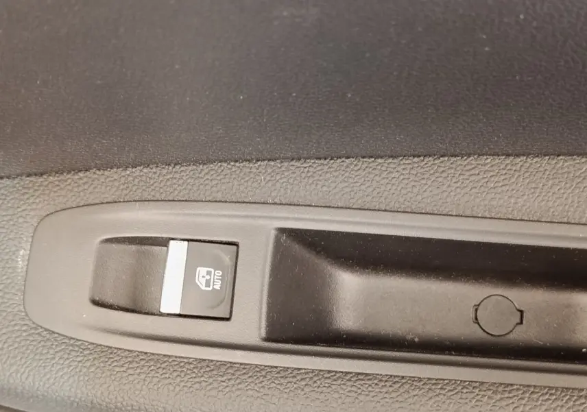 Gros plan sur le bouton de commande de lève-vitre automatique côté conducteur du Renault Captur gris clair Intens E-TECH 2021.