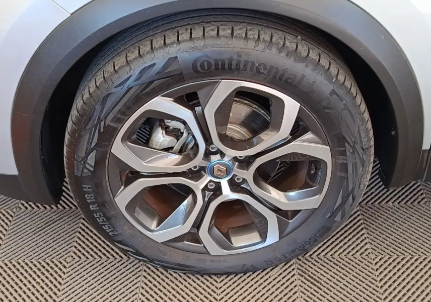 Gros plan sur la roue arrière droite d’un Renault Captur gris clair, avec passage de roue noir et sol en damier.