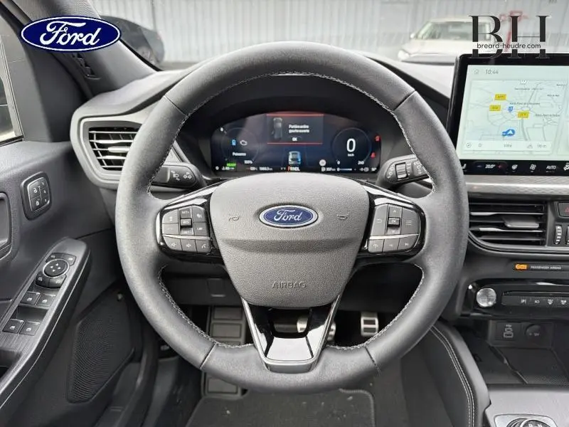 Vue intérieure centrée sur le volant multifonction noir du Ford Kuga 2026 avec tableau de bord numérique et écran tactile GPS.