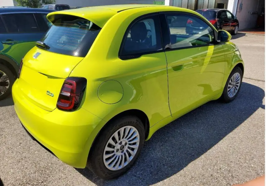 Fiat 500 électrique jaune Acid vue 3/4 arrière côté droit, avec feux arrière foncés et jantes multibranches.