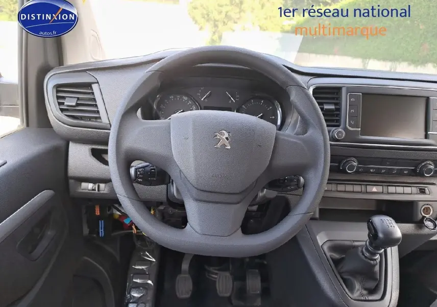 Vue intérieure du poste de conduite du Peugeot Expert Blanc Kaolin, volant et levier de vitesse manuelle visibles.