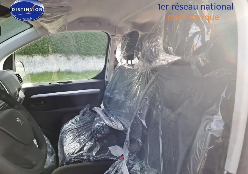 Vue intérieure côté conducteur du Peugeot Expert Blanc Kaolin 2023, sièges avant protégés par film plastique.