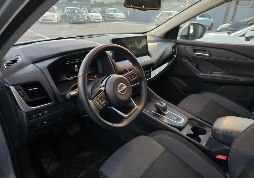 Intérieur du Nissan Qashqai 2024 vu côté conducteur, volant cuir et écran tactile central visible.