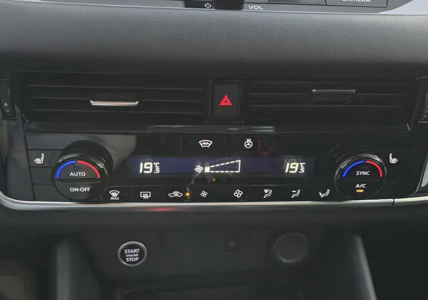 Tableau de bord du Nissan Qashqai 2024 avec climatisation automatique bi-zone et bouton start/stop en vue frontale rapprochée.