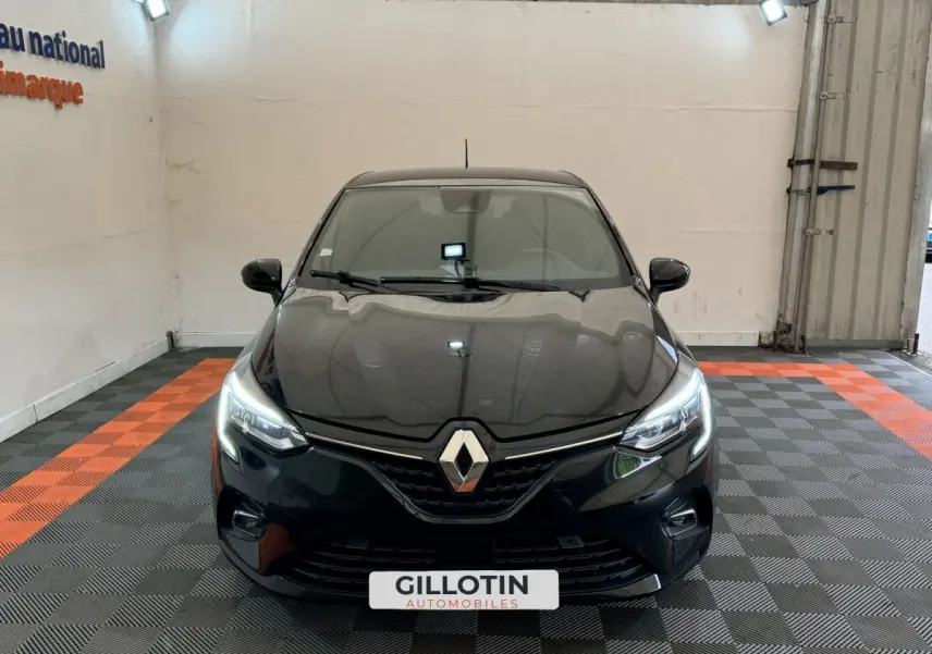 Vue avant d'une Renault Clio Intens TCe 100 noire avec phares LED allumés dans un showroom.