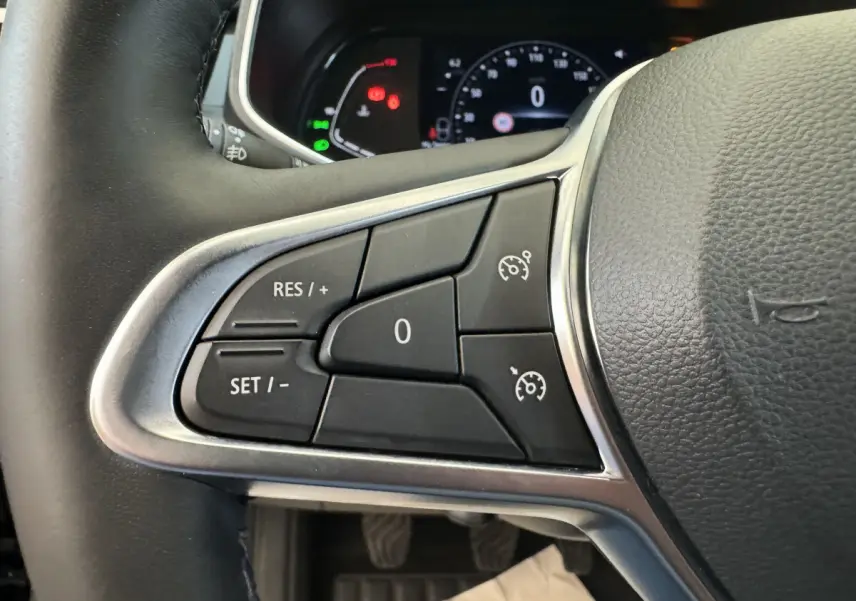 Gros plan sur les commandes du régulateur de vitesse au volant cuir noir de la Renault Clio Intens TCe 100 2020.