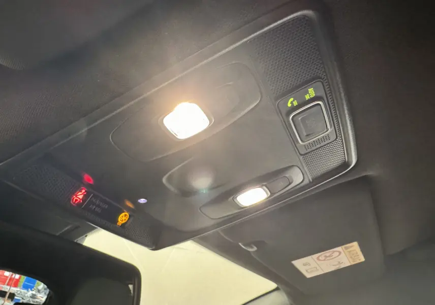 Plafonnier intérieur allumé avec commandes et avertissements sur toit noir d'une Renault Clio Intens TCe 100 2020.