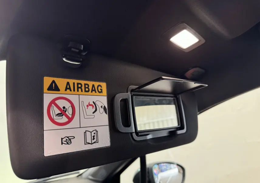 Détail du pare-soleil côté conducteur avec miroir ouvert et avertissement airbag dans Renault Clio Intens noir 2020.
