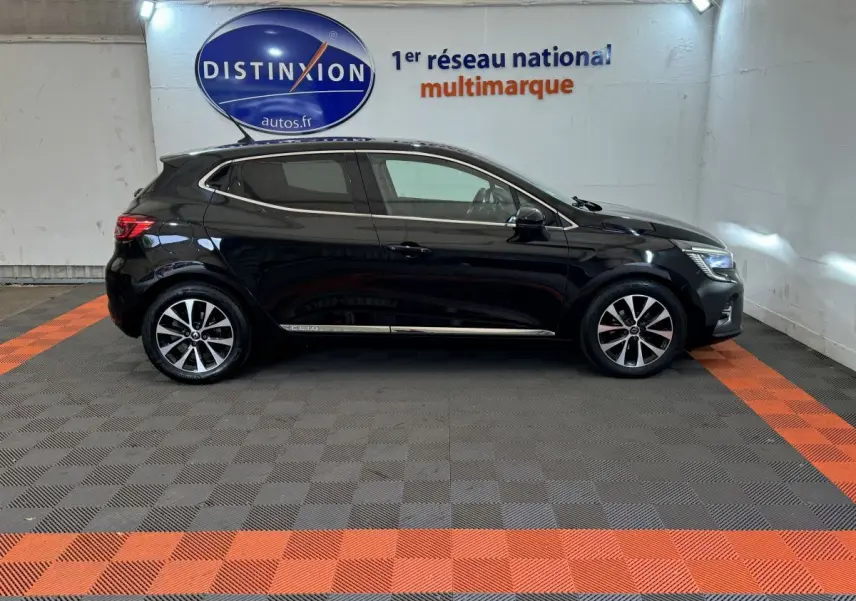 Profil côté gauche d'une Renault Clio Intens TCe 100 noire 2020, stationnée en intérieur sur sol à damiers gris et orange.