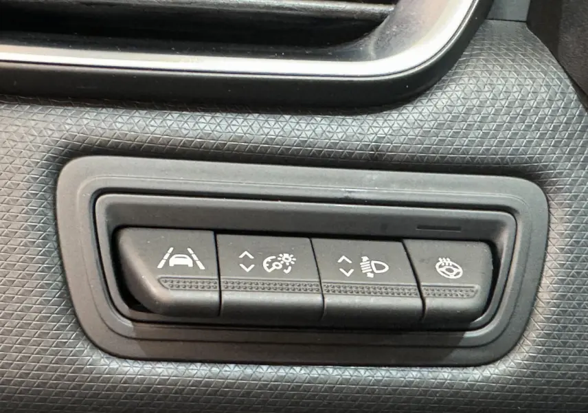 Boutons de réglage d'aide à la conduite et éclairage sur tableau de bord noir texturé d'une Renault Clio Intens 2020.