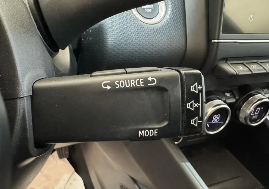 Gros plan sur la commande multimédia noire à gauche du volant dans l'habitacle de la Renault Clio Intens 2020.