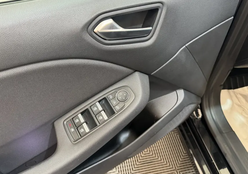 Gros plan sur la porte côté conducteur de la Renault Clio Intens TCe 100 noire, montrant les commandes des vitres électriques.