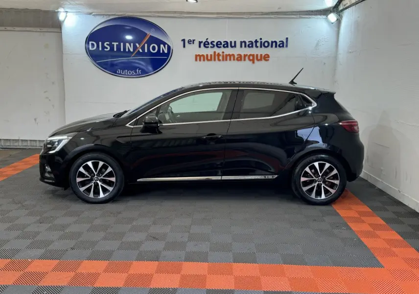 Profil côté gauche d'une Renault Clio Intens noire 2020 avec jantes alliage et vitres teintées en intérieur showroom.