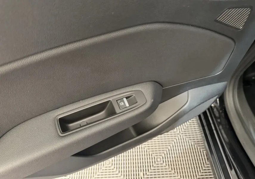 Gros plan sur la poignée intérieure de la porte côté conducteur d'une Renault Clio Intens TCe 100 noire de 2020.