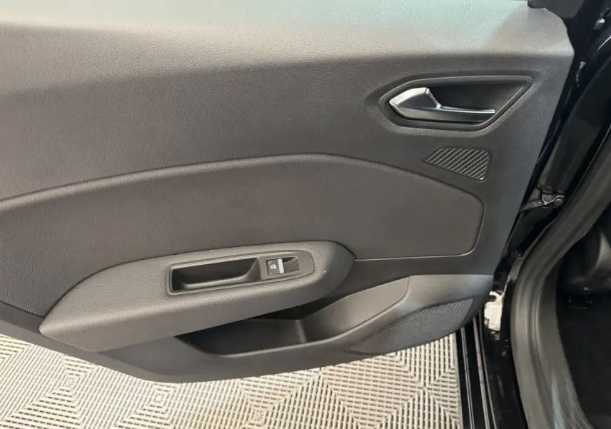 Vue rapprochée de la porte intérieure côté droit noire de la Renault Clio Intens TCe 100, avec poignée et commande de lève-vitre.