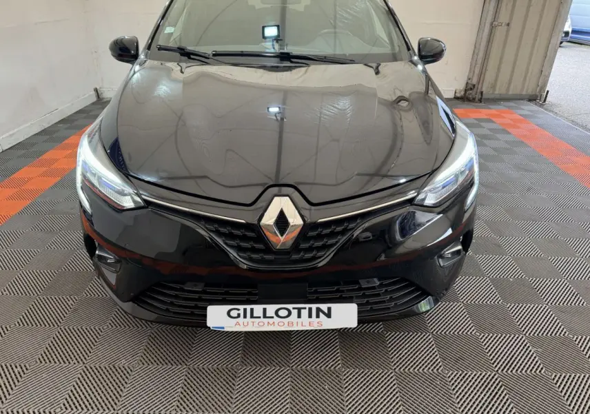 Vue frontale rapprochée d'une Renault Clio Intens TCe 100 noire avec phares LED allumés en intérieur.