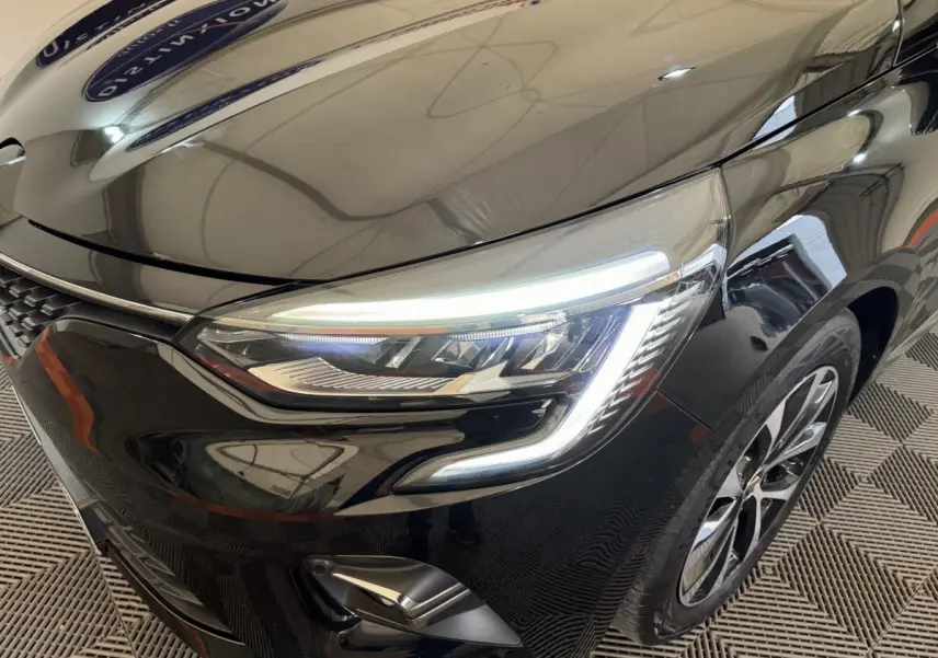 Gros plan sur l'avant droit de la Renault Clio Intens TCe 100 noire, mettant en valeur ses phares LED et jante alliage.
