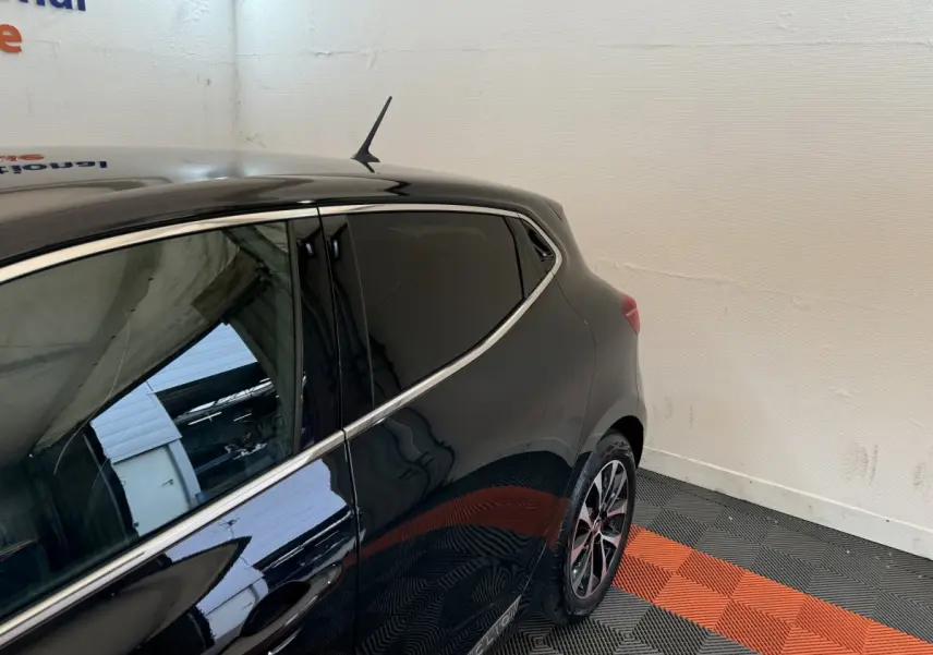 Vue arrière côté gauche d'une Renault Clio Intens TCe 100 noire avec vitres teintées et jantes alliage.