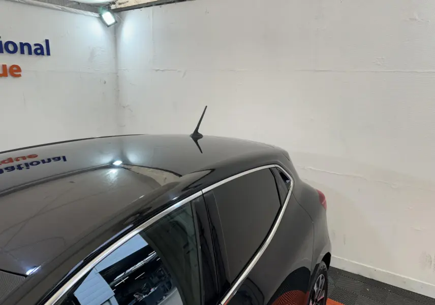 Vue arrière côté gauche d'une Renault Clio Intens TCe 100 noire, avec vitres teintées et antenne de toit.