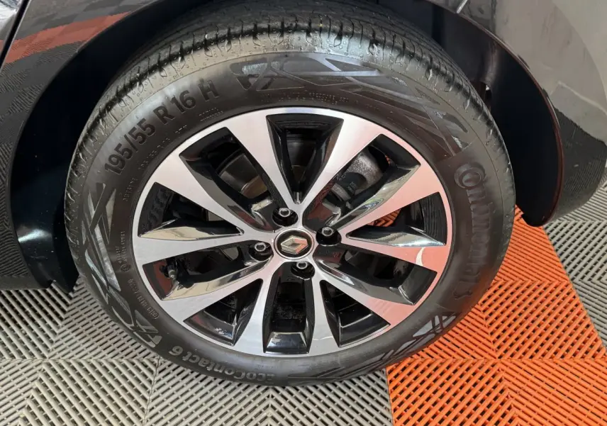 Gros plan sur la roue avant droite noire d'une Renault Clio Intens TCe 100 avec jante alliage bicolore.
